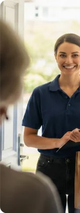 Smiling caregiver holding a clipboard during a home visit.
